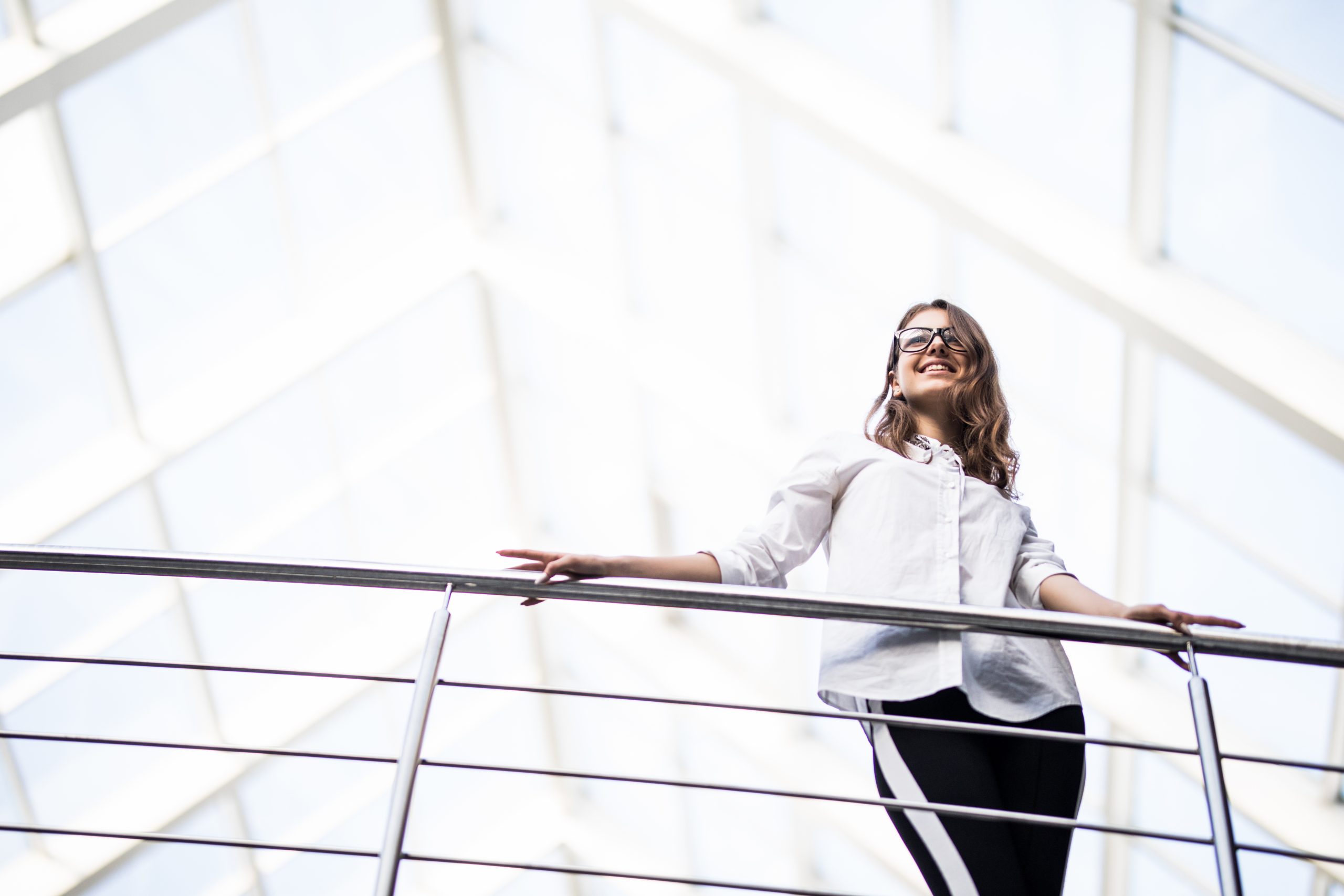 successful business women standing looking through on balcony in modern office centre dressed up in white t shirt